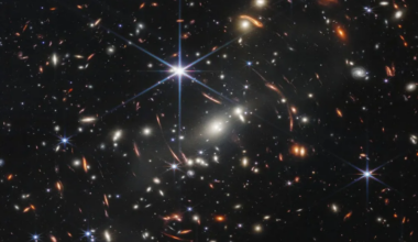 Image of a field of stars and galaxies, with most of them distorted by a gravitational lens.