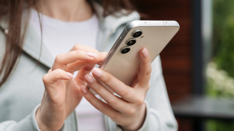 Person using a Samsung Galaxy S23 FE outdoors.