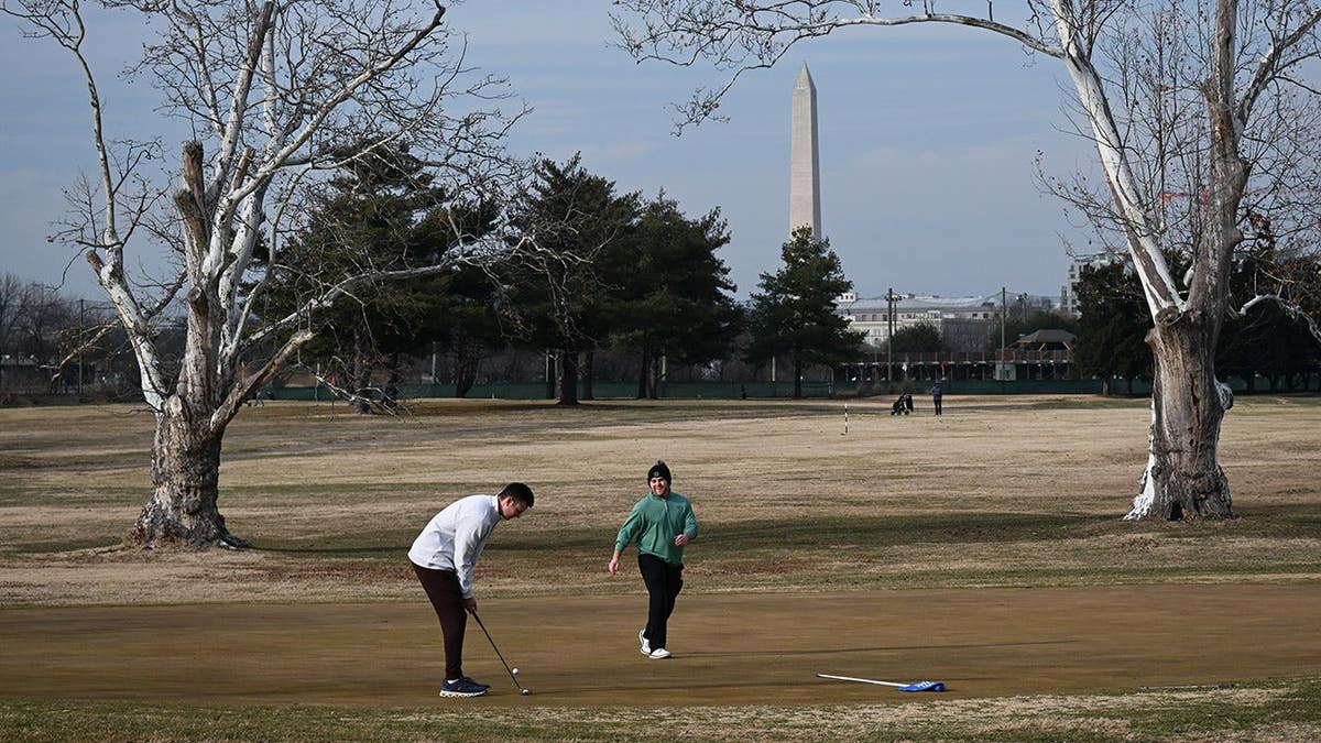 Jack Faraone putting while Cameron Levine reacts at East Potomac Golf Links in Washington, D.C.