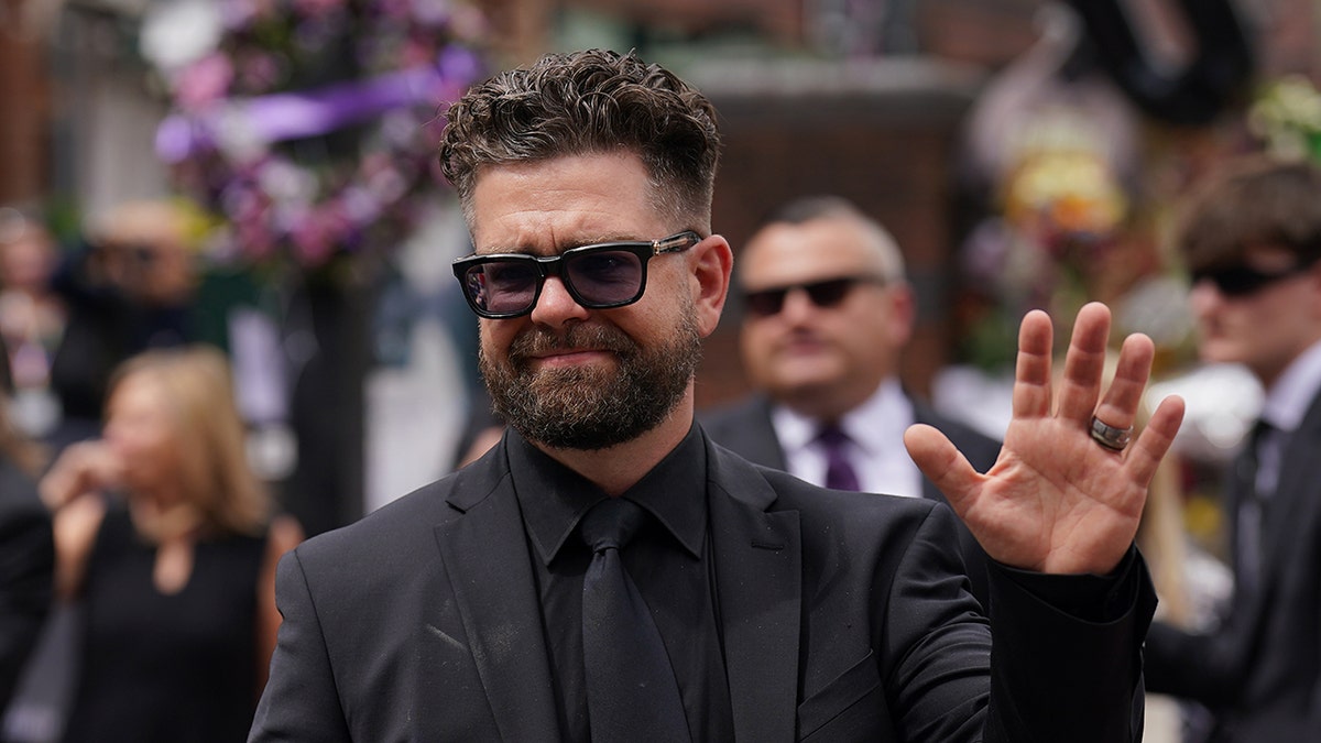 Jack Osbourne waving to crowd at Black Sabbath Bridge bench in Birmingham