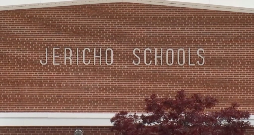 The exterior of a red brick building with the words "JERICHO SCHOOLS" in white letters on the facade.