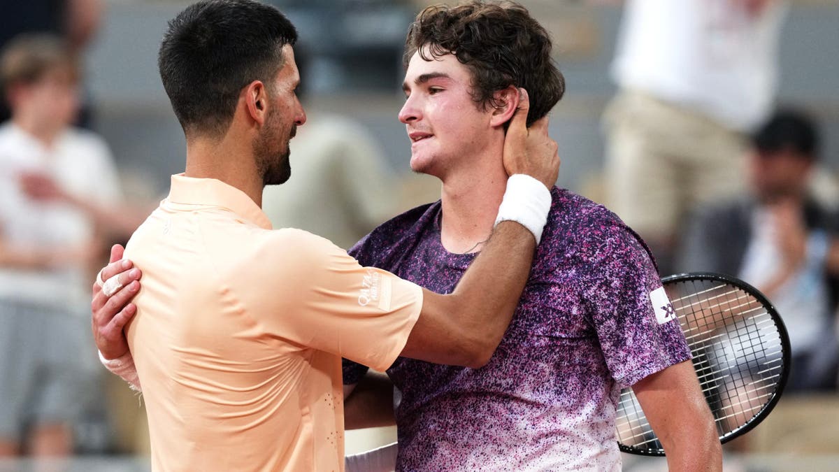 Joao Fonseca greeting Novak Djokovic on tennis court at French Open