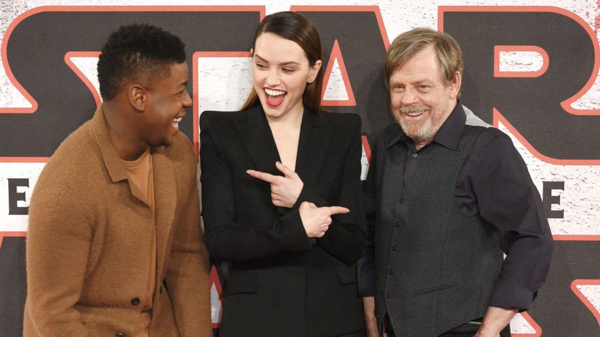 John Boyega, Daisy Ridley, and Mark Hamill posing at a photocall event.