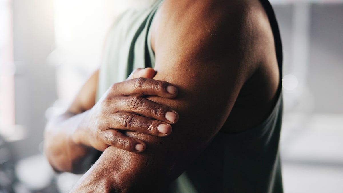 Man holding arm in gym setting