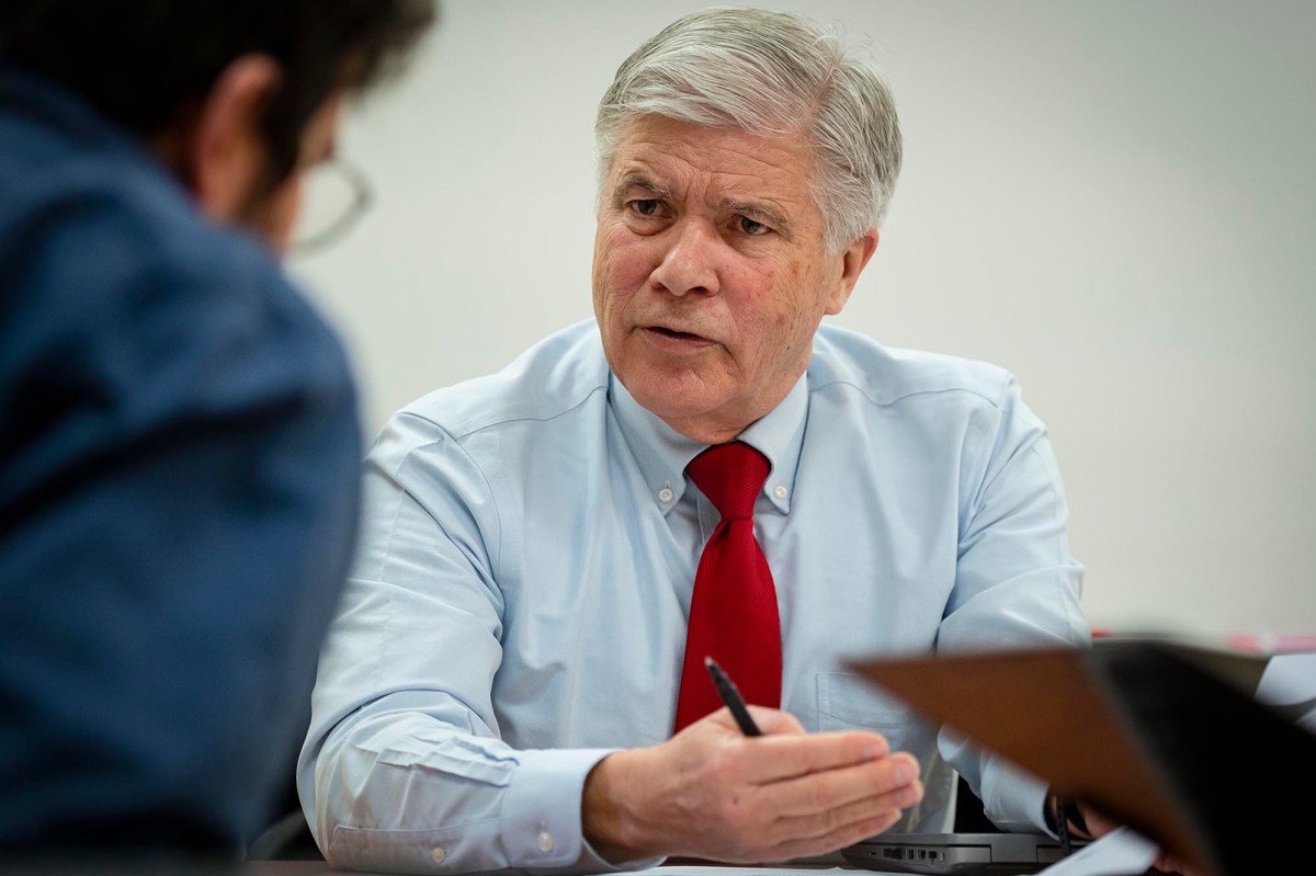 a man in a red tie sitting at a desk.