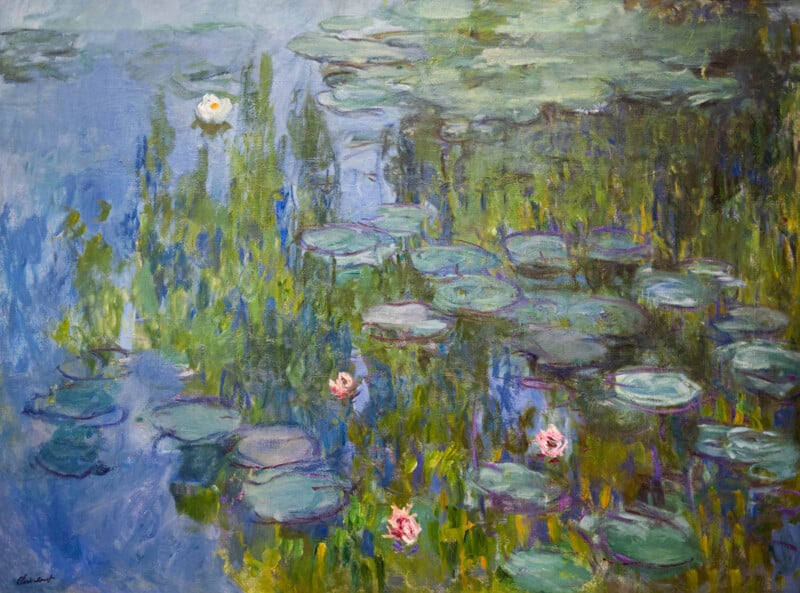 Impressionist painting of a pond with lily pads and blooming pink and white water lilies; reflections of sky and foliage create a serene, colorful atmosphere.