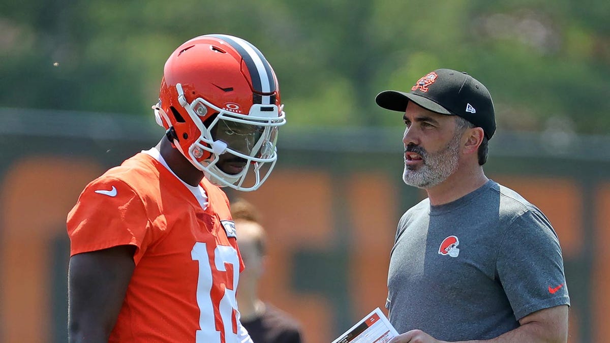 Cleveland Browns quarterback Shedeur Sanders speaking with coach Kevin Stefanski during practice