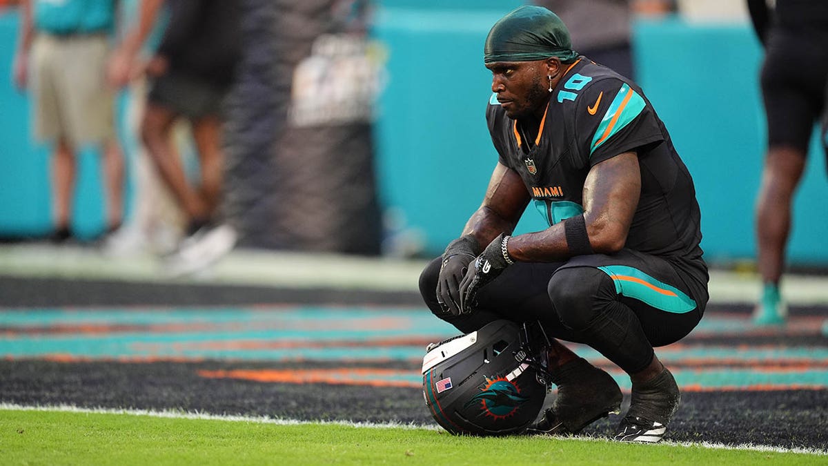 Tyreek Hill standing on the sideline looking toward the field during an NFL game