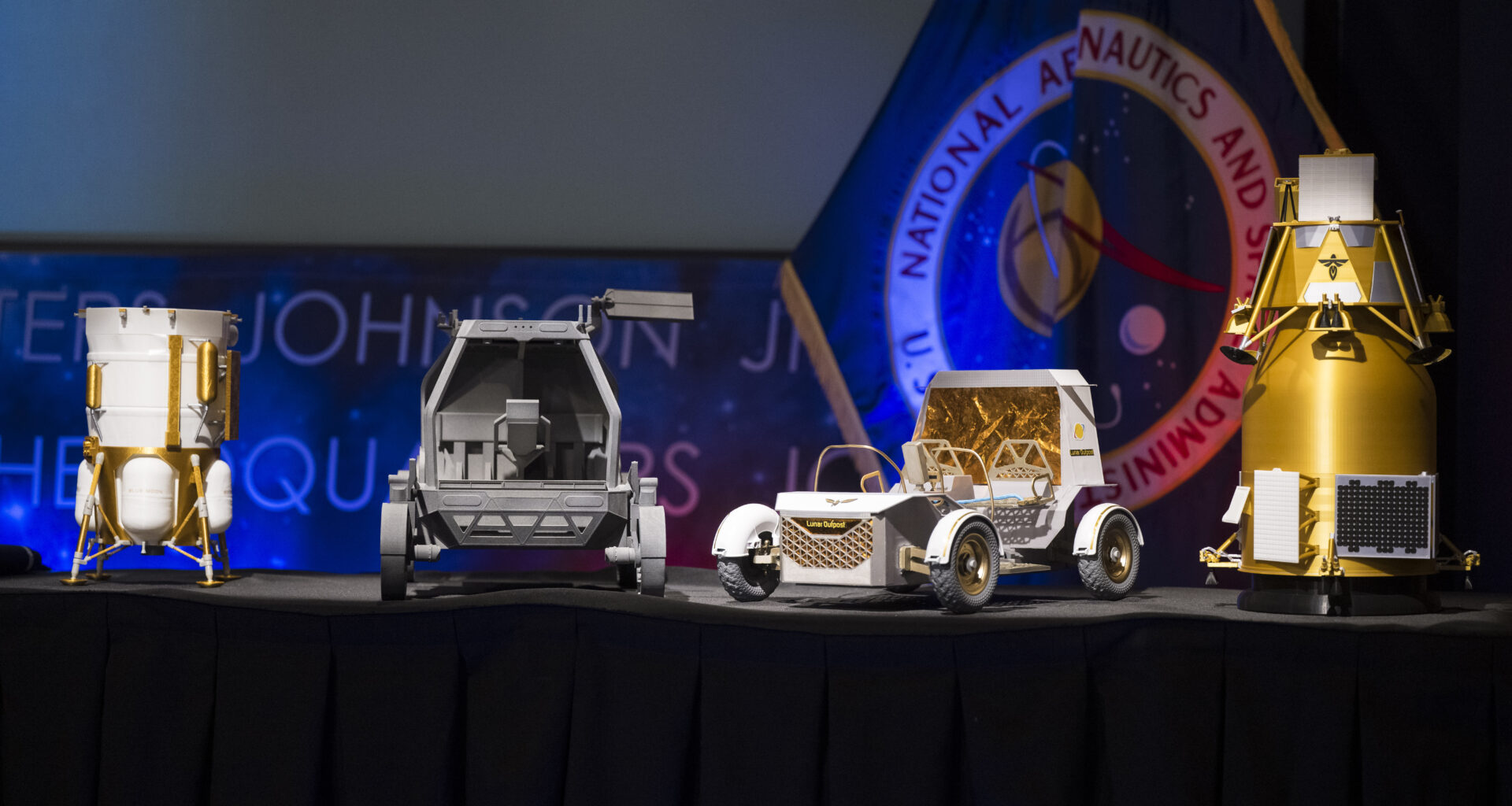 From left to right, models of the Blue Origin Mark 1 Lunar Lander, Astrolab Crewed Lunar Rover, Lunar Outpost Pegasus rover, and the Firely Elytra Dark orbiter are seen at the conclusion of a news conference to discuss Moon Base, a long-term lunar exploration and infrastructure initiative designed to enable sustained human presence and expanded scientific and commercial activity at the lunar South Pole, Tuesday, May 26, 2026, at the Mary W. Jackson NASA Headquarters building in Washington. Photo Credit: (NASA/Aubrey Gemignani)