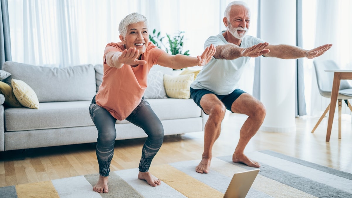 Senior couple doing squats during a workout at home