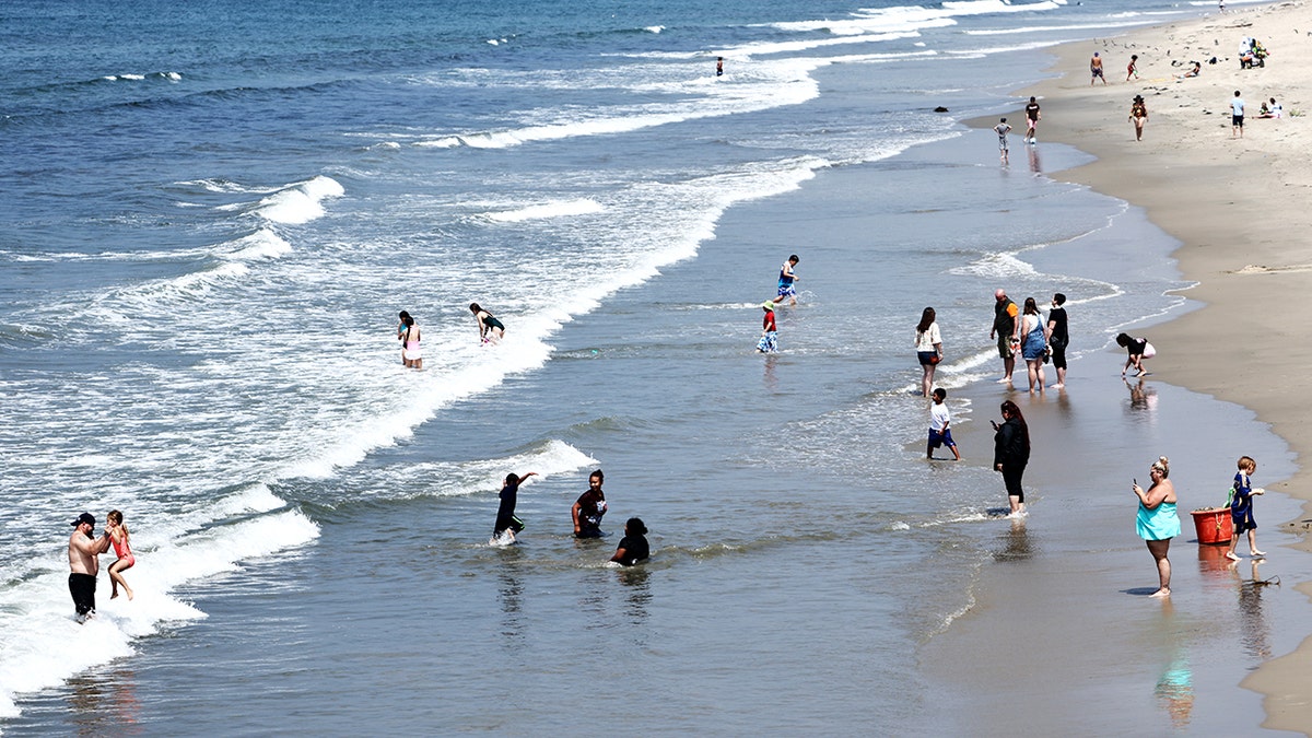 People gathering and swimming on Santa Monica beach during tsunami advisory