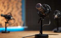 Soft focus of modern microphone placed on wooden table in recording studio during podcast