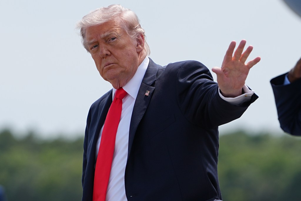 President Donald Trump arriving at Ocala International Airport, raising his hand to wave.