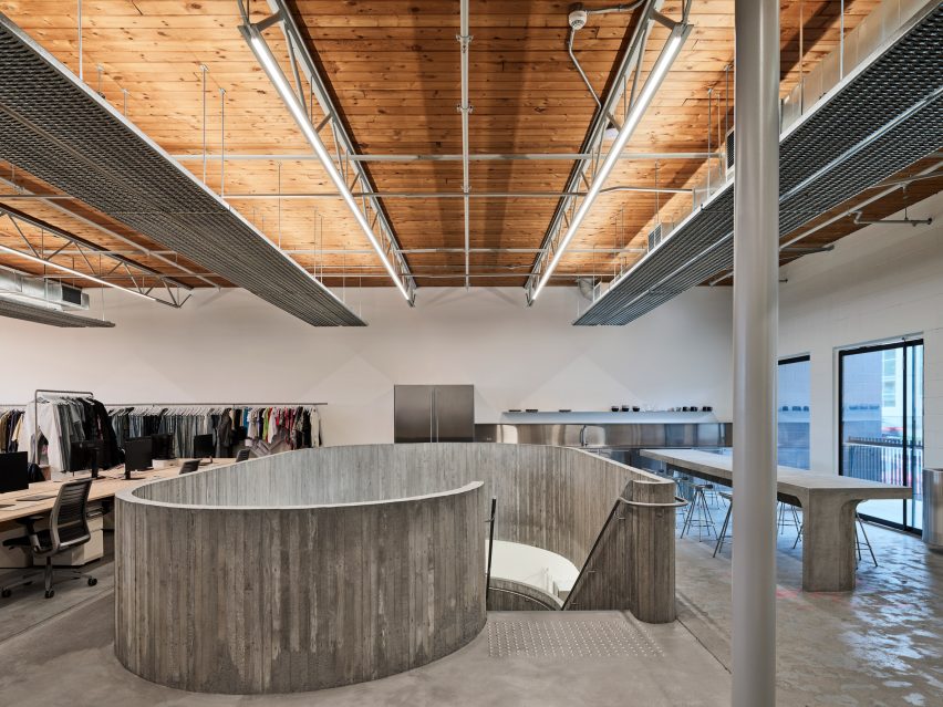 A large opening is cut into a concrete floor to make room for a staircase connecting the two levels