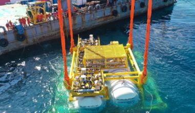 A submersible data center pod is lowered underwater via crane.