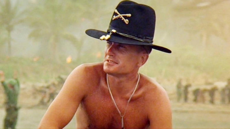 A shirtless Robert Duvall crouches down on a Vietnam beach as Colonel Bill Kilgore in Apocalypse Now