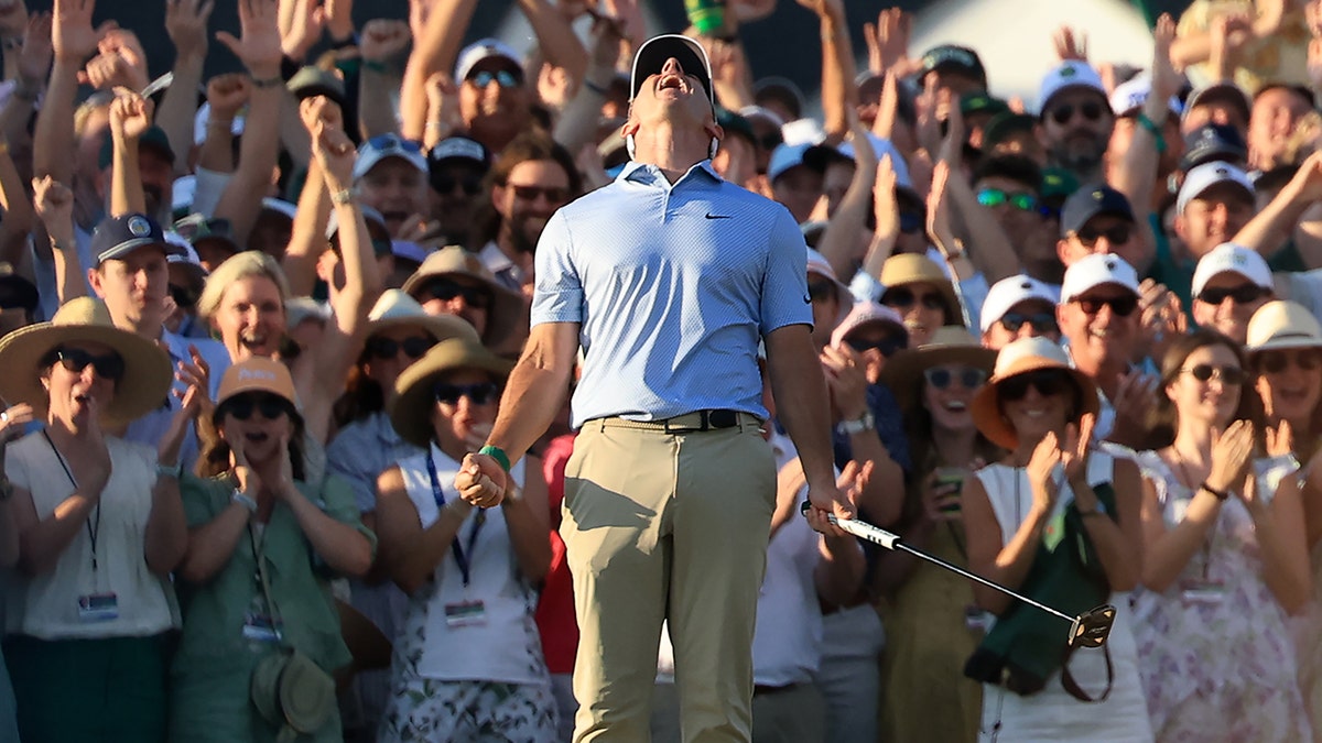 Rory McIlroy celebrating after holing winning putt on 18th green at Augusta National Golf Club