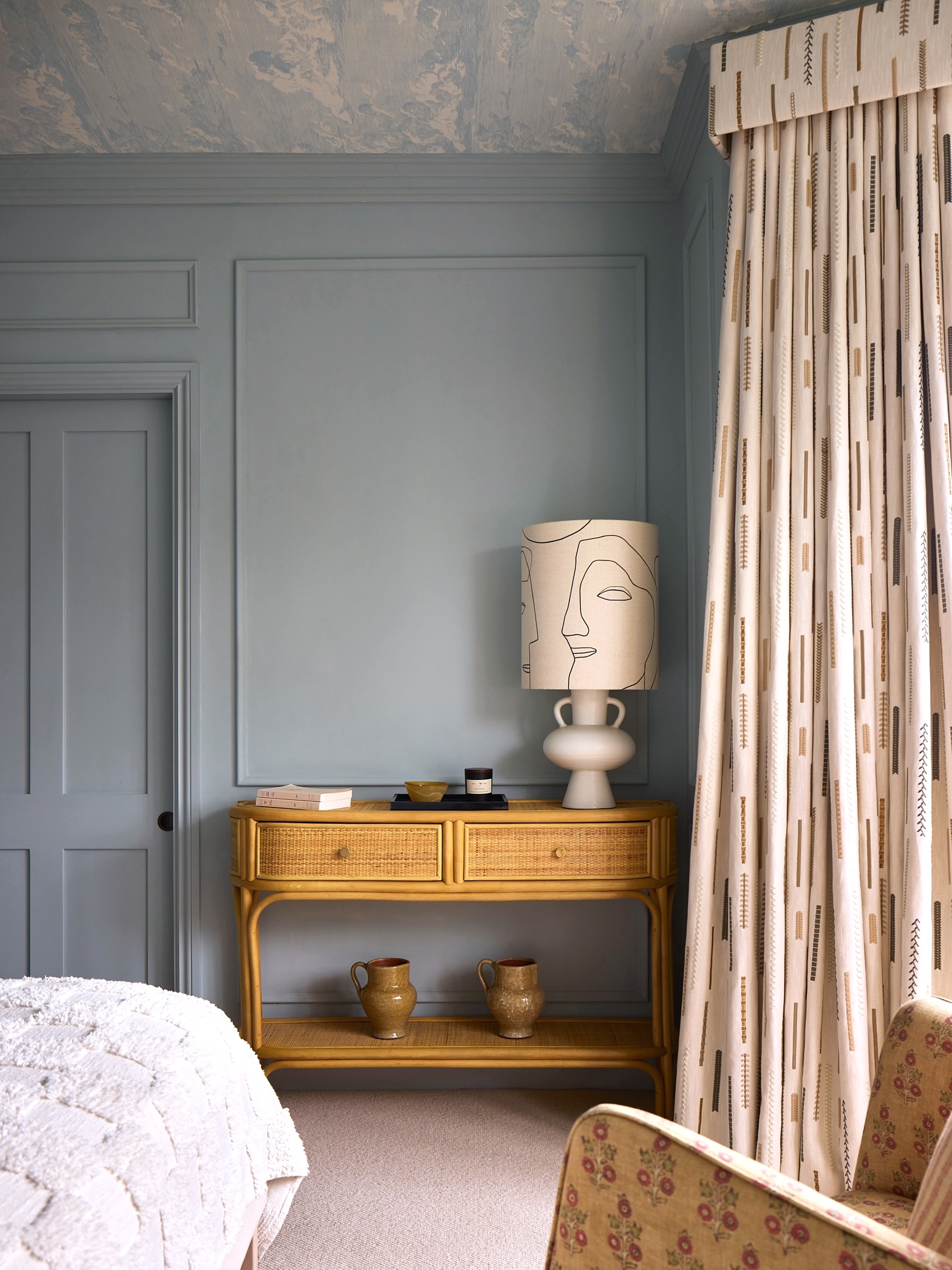 A bedroom painted in mineral blue with cloud wallpaper on the ceiling
