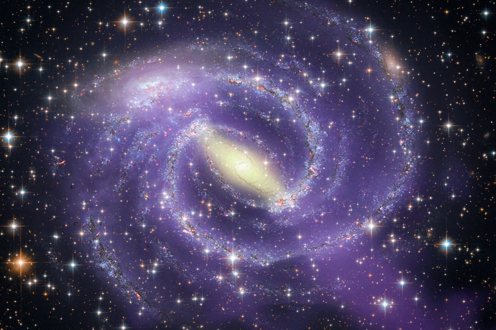 A purple and yellow spiral galaxy against a dark, star-filled sky.