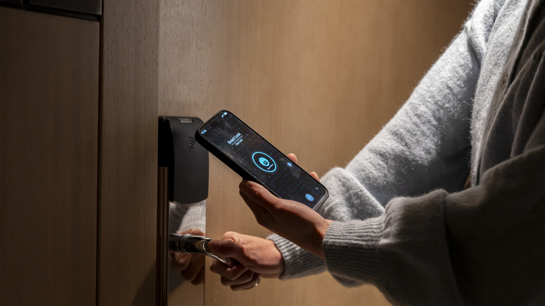 A person unlocking a room door using an app on a mobile phone
