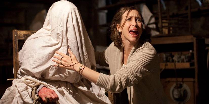 Lorraine Warren, screams while standing next to a possessed person covered by a sheet in 'The Conjuring'.