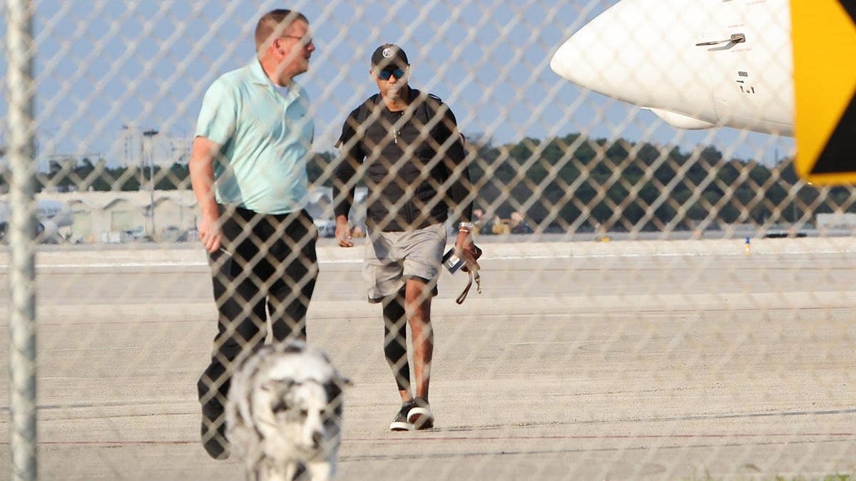 Tiger Woods walking on a tarmac near a private plane in Palm Beach Florida