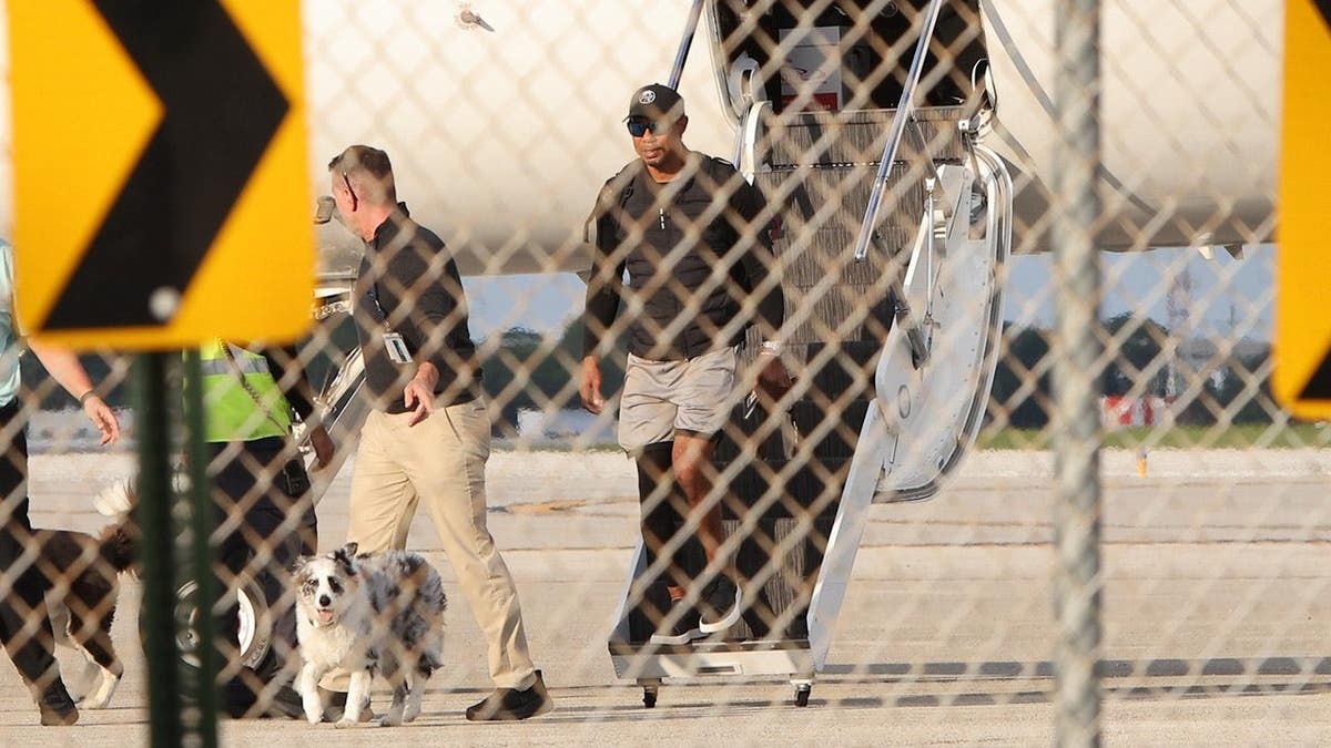 Tiger Woods walking on a tarmac near a private plane in Palm Beach Florida