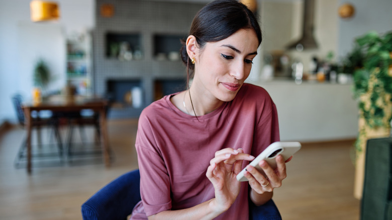Person checking smartphone in home living room