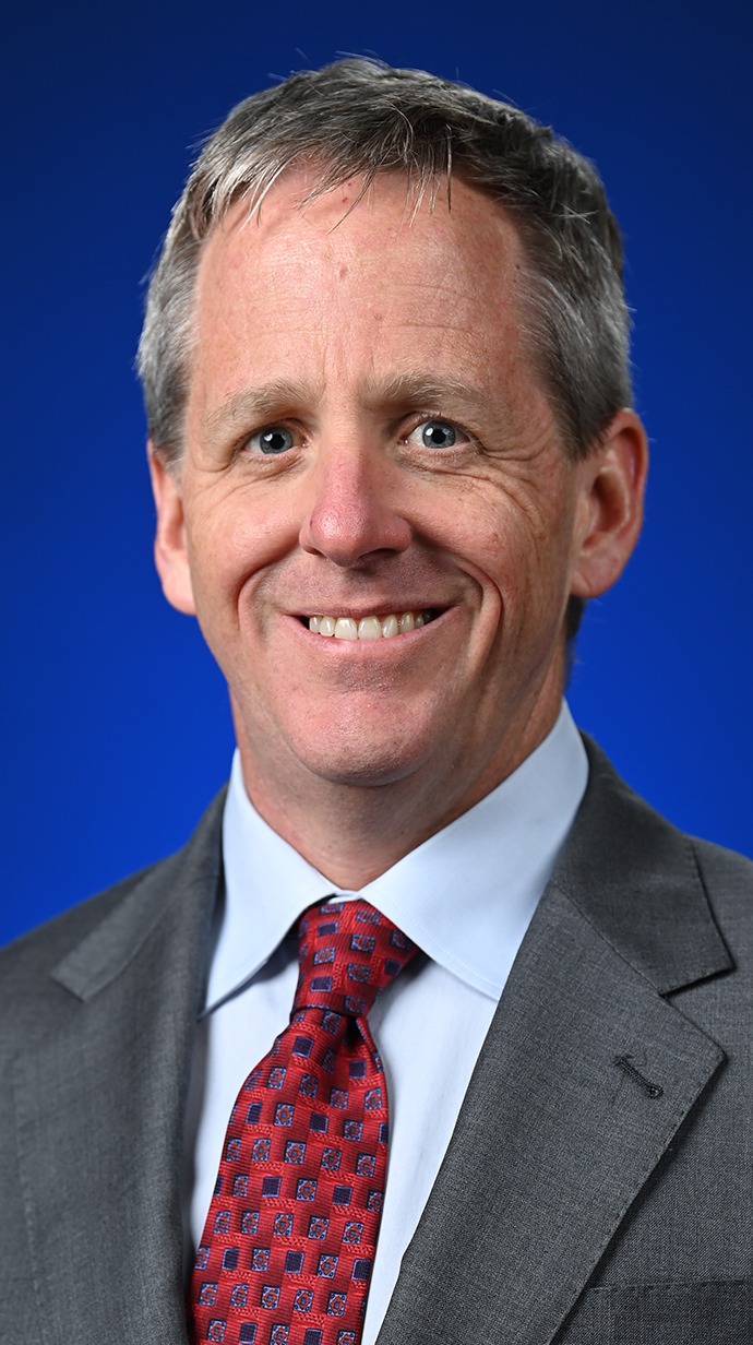 Headshot of a man wearing a gray suit with a red tie.