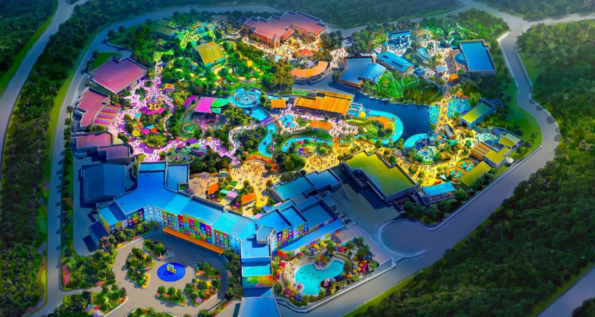 Aerial view of the colorful, illuminated Universal Kids Resort, nestled among dense green trees and winding roads.