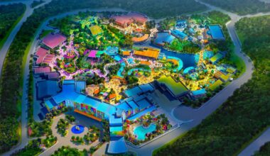 Aerial view of the colorful, illuminated Universal Kids Resort, nestled among dense green trees and winding roads.