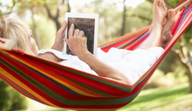 Someone reading a tablet while in a hammock.