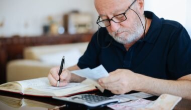 Someone looking at a paper while writing in a book.
