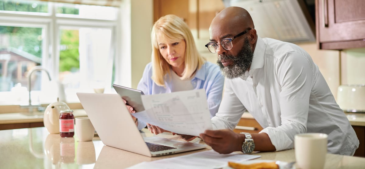Couple looking at documents and laptop together.