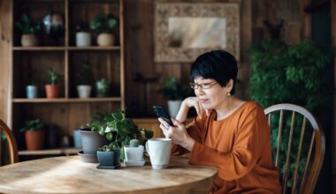 A person sitting at a dining room table looking at a smartphone.