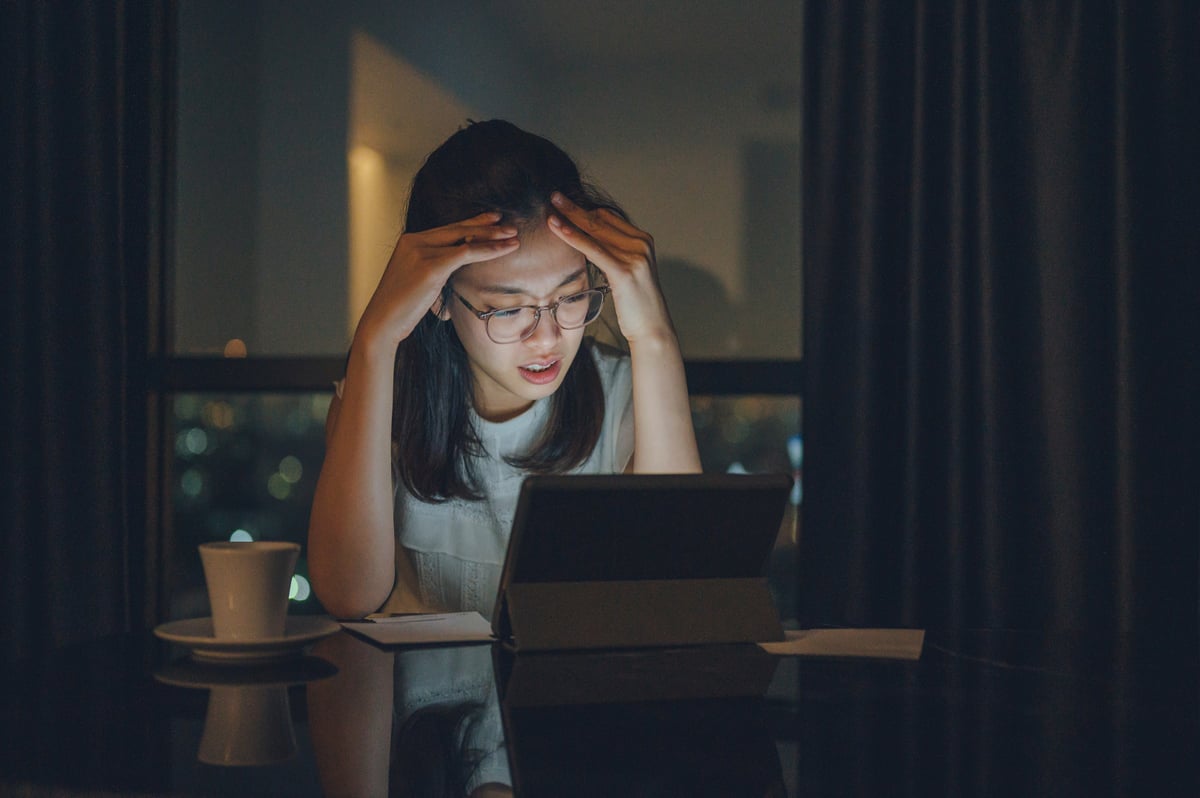 Concerned young person with head in hands gazing at a screen.