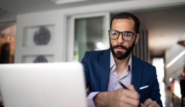 Serious person looking at laptop and writing note.