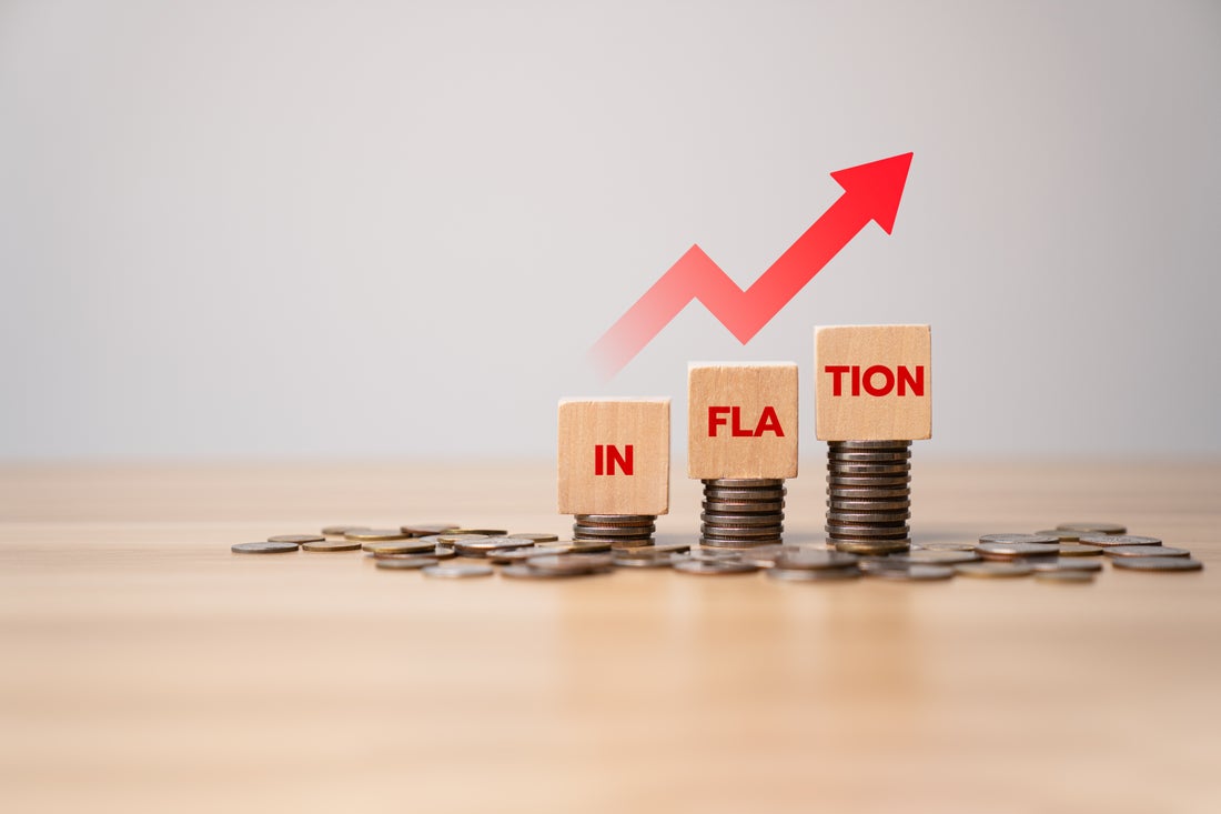 Three stack of coins, each larger than the one before. Each stack has a block balanced on top. The three blocks spell out the word "Inflation."