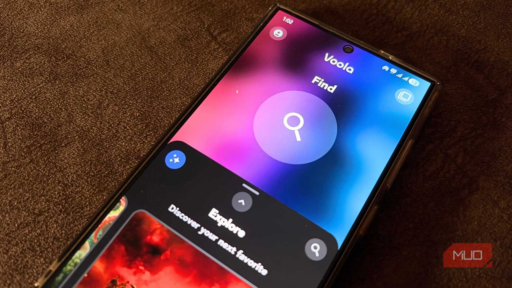 Samsung Galaxy phone lying flat showing Voola app's Find screen with gradient purple and blue background