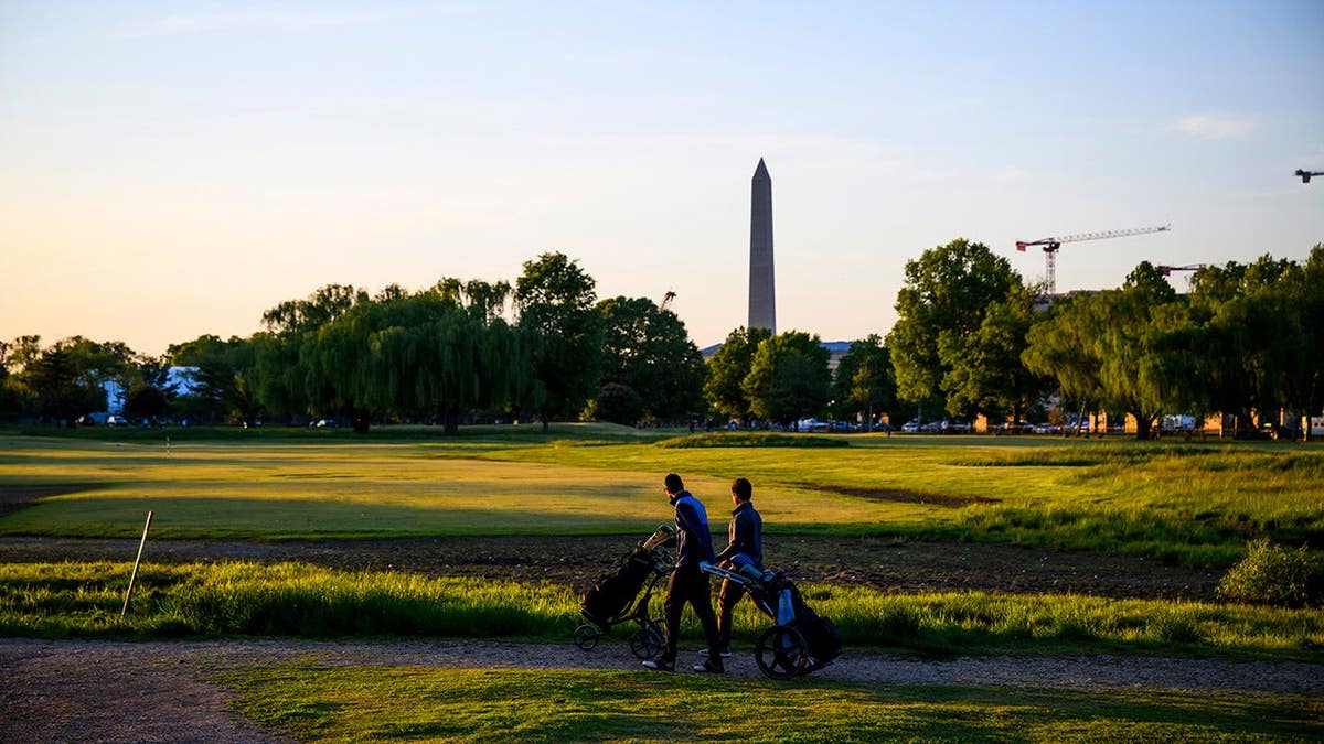 People playing golf at East Potomac Golf Links with Washington Monument in background