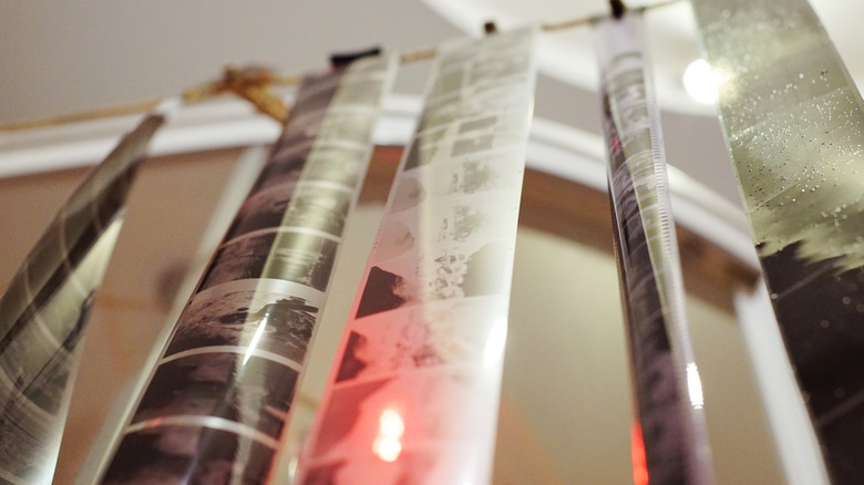Physical film rolls hanging in a darkroom for developing.