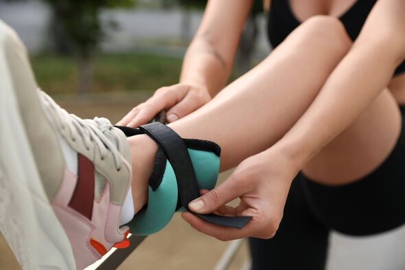 Woman putting on ankle weight outdoors, closeup Woman putting on ankle weight outdoors, closeup