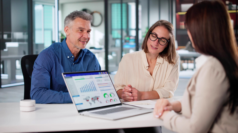 A Gen X couple speaking to a wealth manager in a financial institution.