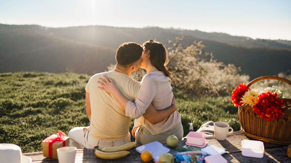 Young man kissing a woman during a picnic on a mountain