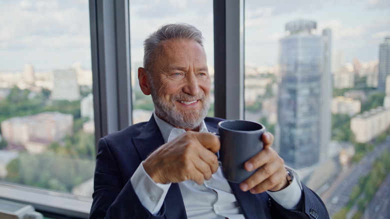 A wealthy senior drinking coffee in skyrise room