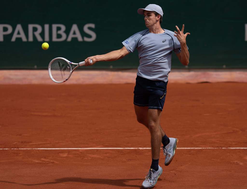 Zachary Svajda hitting a forehand return during a tennis match at the French Open.