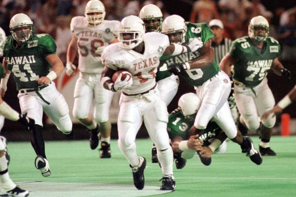 Ricky Williams, wearing a number 11 jersey, tries to pull away from a Hawaii defender