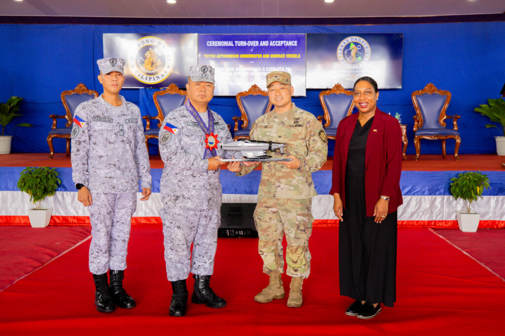 U.S. Embassy Senior Defense Official and Chief of the Joint US. Military Assistance Group-Philippines Colonel Daniel Oh (second from right) presents Philippine Fleet Commander Rear Admiral Joe Anthony Cabahug-Orbe (second from left) with a scale model of the Ocean Aero Triton autonomous underwater and surface vehicle during the turnover ceremony at the Philippine Navy’s Naval Operating Base Subic on June 22.  They are joined by U.S. Embassy Chargé d’Affaires, a.i., Bridgette Walker (rightmost) and Philippine Navy Unmanned Surface Vessel Unit Acting Commander Lt. Cmdr. Aldwin Pasicolan (leftmost). 