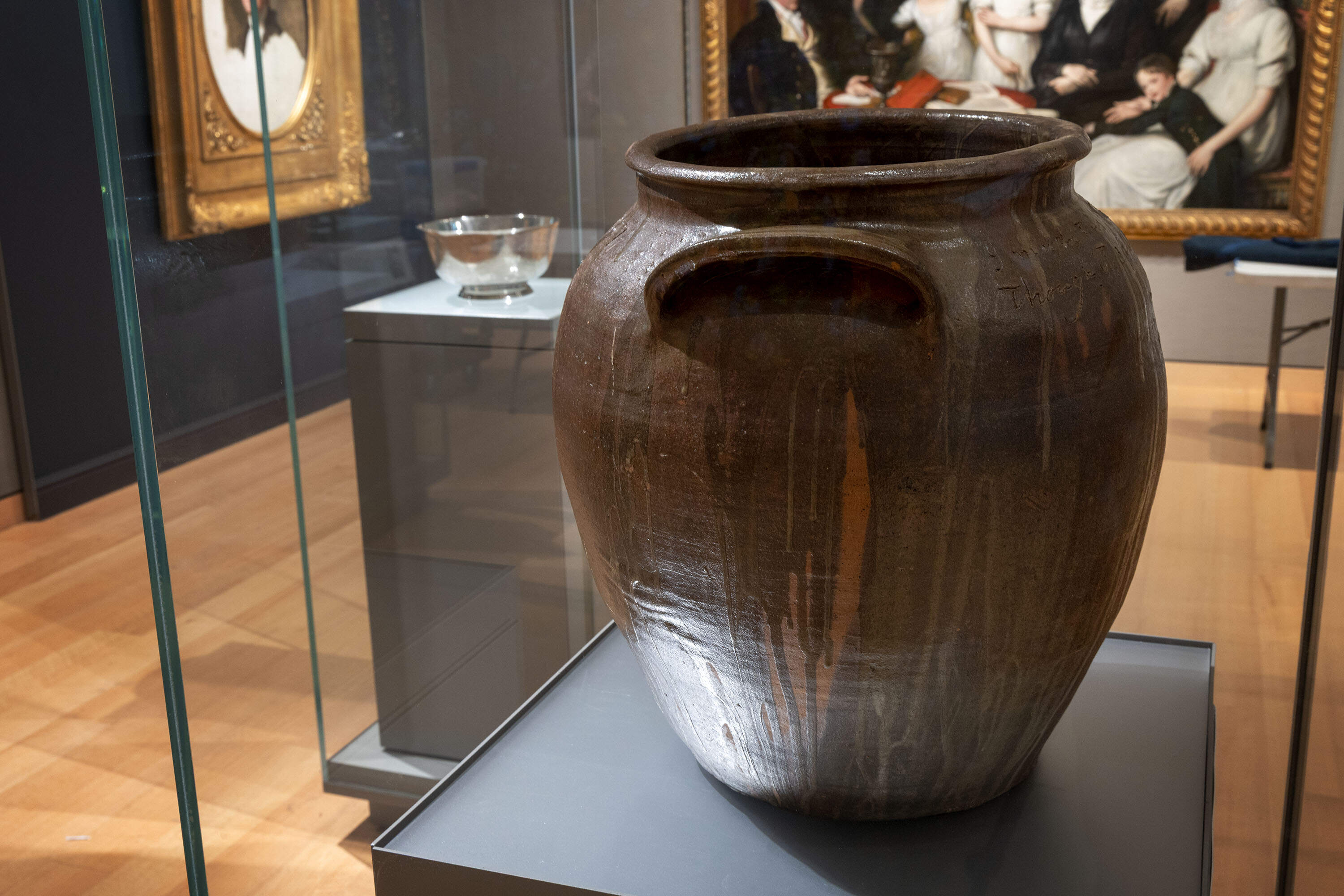 A large clay jar by enslaved artist David Drake stands on display by Paul Revere's “Liberty Bowl” at the MFA in Boston. (Robin Lubbock/WBUR)