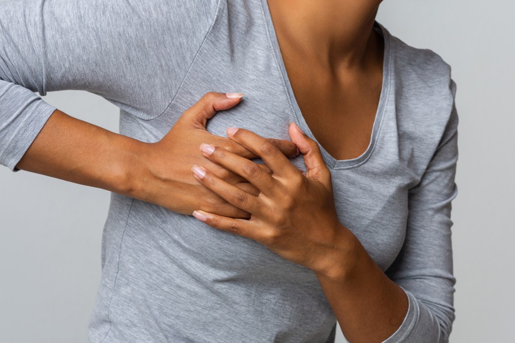 Person in gray shirt holding their chest in pain.